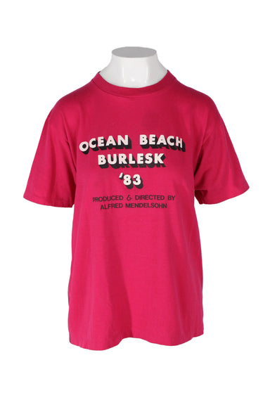 vintage sportswear bright pink t-shirt. features screen print in white with black shadow reading 'ocean beach burlesk 83' across chest, short sleeves, round ribbed collar, and single stitch hem. 